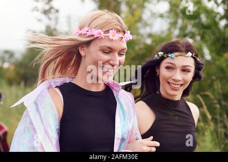 Zwei neugierige Junge weibliche Freunde an Musik Festival Wandern durch Feld Stockfoto