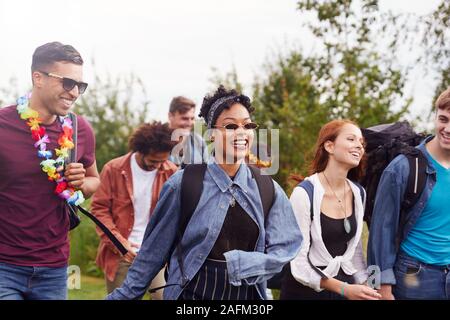 Gruppe der aufgeregten Jungen Freunde, die Camping Ausrüstung durch das Feld Musik Festival Stockfoto