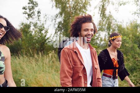 Gruppe der aufgeregten Jungen Freunde, die Camping Ausrüstung durch das Feld Musik Festival Stockfoto