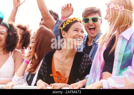 Jubelnde Junge Freunde im Publikum hinter der Barriere an Outdoor Festival Musik genießen Stockfoto