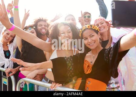 Junge Freunde im Publikum hinter der Barriere an Outdoor Musik Festival Posieren für Selfie Stockfoto