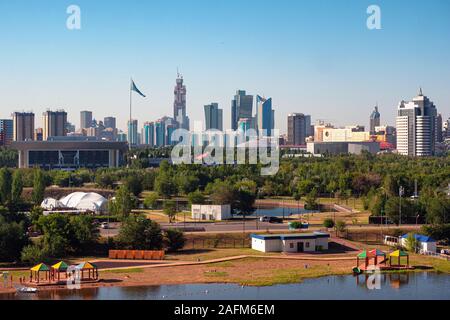 Nur-Sultan, Kasachstan - Juli 15, 2019: Blick auf das Ufer des Flusses Ischim. Im Hintergrund ausgesetzt sind Gebäude und den Bau des Stockfoto