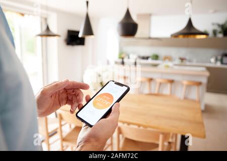 Nahaufnahme von Mann mit App auf Smart Phone Control Zentralheizung Temperatur im Haus Stockfoto