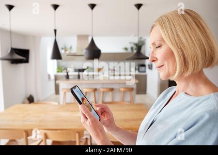 Reife Frau mit "App auf digitalen Tablette, Zentrale Heizung Temperatur im Haus Stockfoto