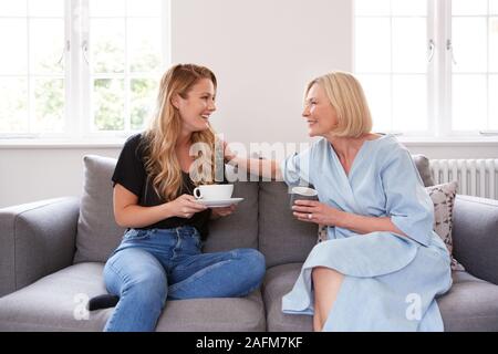 Ältere Mutter, die mit erwachsenen Tochter sitzen auf dem Sofa Zuhause Kaffee Trinken und Reden Stockfoto