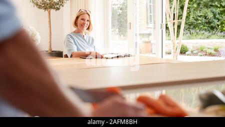 Ältere Menschen folgende Rezept auf digitalen Tablette wie Frau sitzt am Esstisch Eine liest Magazin Stockfoto