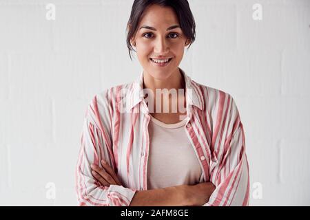 Portrait von lächelnden Leger gekleidete Frau gegen Weiße Brick Studio Wand Stockfoto