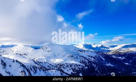 Eine Winterlandschaft der Berge. Sonne scheint in den Himmel. In den Bergen hängen vollständig abgedeckt mit einer dicken Schicht Schnee. Wenige Bäume auf der Piste. Stockfoto