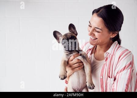 Studio Shot lächelnde junge Frau mit liebevollen Haustier Französisch Bulldog Welpen Stockfoto