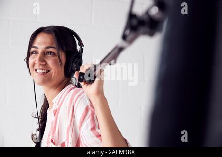 Weibliche Sound Recordist Holding Mikrofon auf Video Film Produktion in White Studio Stockfoto