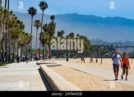 Ein paar Spaziergänge an einem Weg am Strand entlang Seite Palmen gesäumten Boulevard Cabrillio in Santa Barbara, CA, Stockfoto