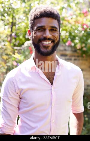 Portrait von lächelnden Mann zu Hause im Garten gegen das Abfackeln von Sun Stockfoto