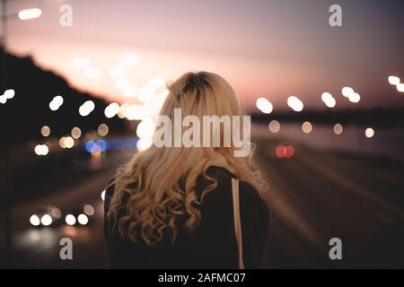 Ansicht der Rückseite des jungen Frau an der Straße stehend auf der Suche auf der Brücke in der Stadt Stockfoto