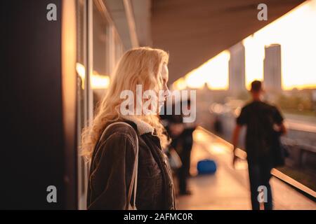 Junge Frau mit blonden Haaren wartet auf Zug in der Nähe der U-Bahn Station Stockfoto