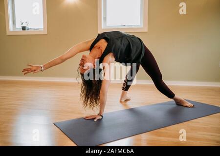 Frau mit schwarzen übt Yoga auf einer Matte in einem Studio Stockfoto