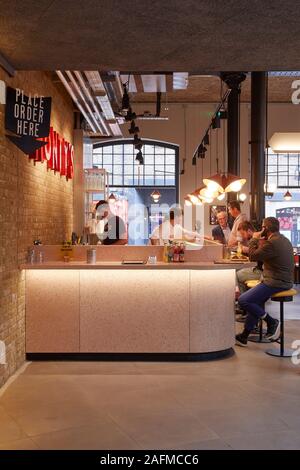 Essen Zähler mit Kunden im Erdgeschoss. Seven Dials Markt, London, Vereinigtes Königreich. Architekt: Steif+Trevillion Architekten, 2019. Stockfoto