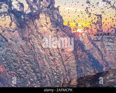 Romantischer Sonnenuntergang durch eine steinige Hafenpromenade. Die Sonne über dem Horizont. Die Sonnenstrahlen in das ruhige Meer widerspiegelt. Steinigen Ufer ist von den Wellen weggespült, s Stockfoto