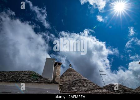 Dächer von truli, typisch weiß getünchten zylindrische Häuser in Alberobello, Apulien, Italien mit tollen blauen Himmel mit Wolken und Sonne Stockfoto