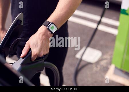 Nahaufnahme von Hand befestigen Sie das Netzkabel auf Umweltfreundliche Emissionsfreie Elektroauto Stockfoto