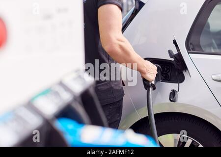 Nahaufnahme von Mann befestigen Sie das Netzkabel auf Umweltfreundliche Emissionsfreie Elektroauto Stockfoto