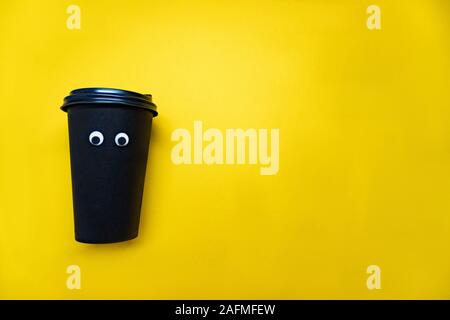 Kaffeetasse mit kulleraugen auf gelbem Hintergrund Stockfoto