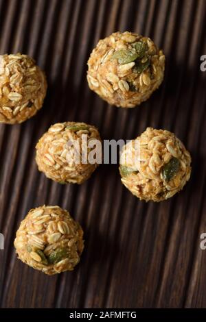 Raw vegan Energie beißt. Hausgemachte Haferflocken Kugeln mit Kürbiskernen auf Eiche dunkel Board Ansicht von oben kopieren Raum Stockfoto