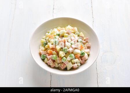 Olivier Salat aus gekochtem Gemüse und Wurst mit Mayonnaise in der Schüssel. Russische Silvester oder Weihnachten Salat auf hellen Hintergrund. Schließen bis vie Stockfoto