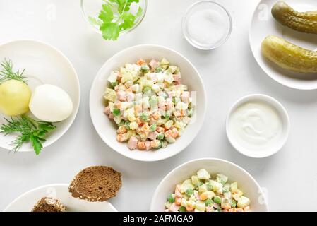 Lecker Olivier Salat aus gekochtem Gemüse und Wurst mit Mayonnaise in der Schüssel. Russische Silvester oder Weihnachten Salat auf hellem Stein Hintergrund. Top vie Stockfoto
