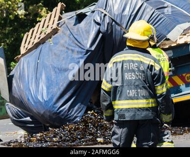 Feuerwehr, Feuerwehr, Rettung, Notfallhelfer bei einem Verkehrsunfall Szene, wo ein Lkw oder Lkw seine Ladung in Kapstadt verloren hat. Stockfoto