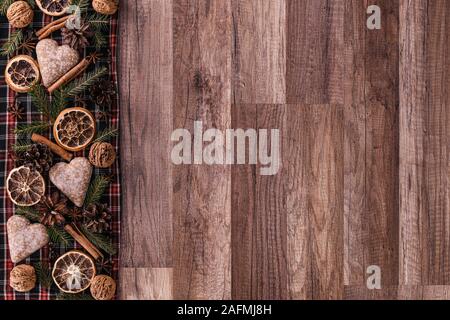 Weihnachtskarte mit Weihnachts-Tannenbaum, Gewürzen Zimtstäbchen, Anisstern, Orangen und Ingwerbrot auf rustikalem Holzhintergrund. Stockfoto