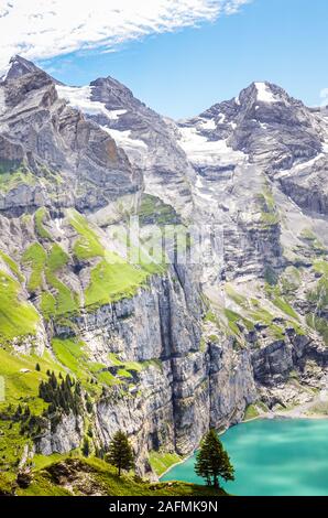 Vertikale Foto der schönen Oeschinensee See von Kandersteg, Schweiz. Türkisfarbenen See durch steile Berge und Felsen umgeben ist. Schweizer Alpen. Schweiz in der Sommersaison. Touristische Attraktion. Stockfoto