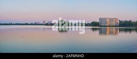 Die ruhige Panoramablick auf die Oberfläche von Inya See den klaren Abendhimmel, Silhouette von dunklen Bäumen und Hochhäuser auf dem Abstand, Yangon, Myanmar Stockfoto