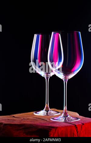 Zwei leere Gläser für einen Wein, der am Holztisch und dunklen Hintergrund Stockfoto