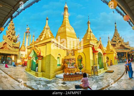 YANGON, MYANMAR - Februar 17, 2018: Panorama der herausragenden mittelalterlichen Sule Paya, bestehend aus goldenen Stupa, durch kleine Schreine umgeben, Bild Häuser Stockfoto