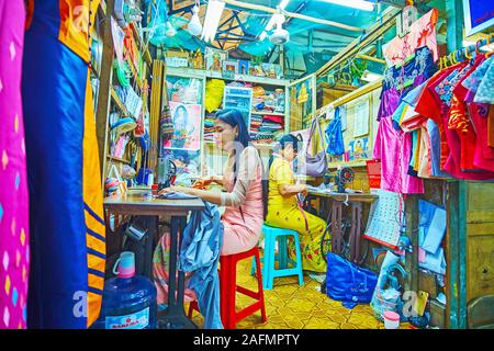 YANGON, MYANMAR - Februar 17, 2018: das Innere der Nähwerkstatt mit zwei Arbeiten Näherinnen in der Bogyoke Aung San Markt, am 17. Februar in Yangon. Stockfoto