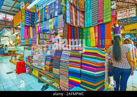 YANGON, MYANMAR - 17. FEBRUAR 2018: Die mit verschiedenen Textilien und Birmanische paso longyi (männlich und weiblich) in Htamein Bogyoke Aung San Market, o Abschaltdruck Stockfoto