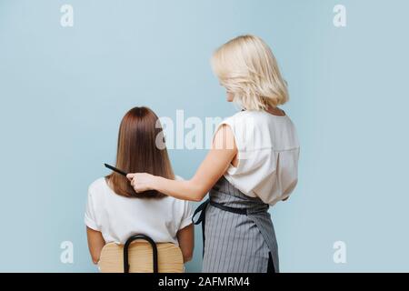 Friseur Frau kämmen Client gerade Haar über glitzernden blauen Hintergrund. Stockfoto