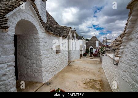 Dächer und Tore von truli, typisch weiß getünchten zylindrische Häuser in Alberobello, Apulien, Italien mit tollen blauen Himmel mit Wolken, Street View Stockfoto