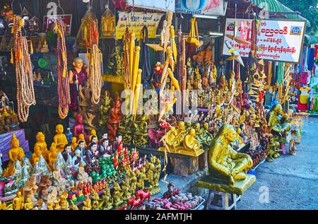 YANGON, MYANMAR - 17. FEBRUAR 2018: Die Stände der traditionelle Markt in Ar Zar Ni Straße mit buddhistischen Kult waren - Bilder von Buddha, Statuetten von Stockfoto
