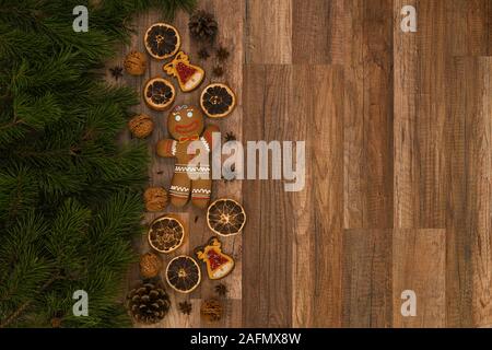 Weihnachtskarte mit Tanne und Ingwerbrot auf rustikalem Holzhintergrund. Stockfoto