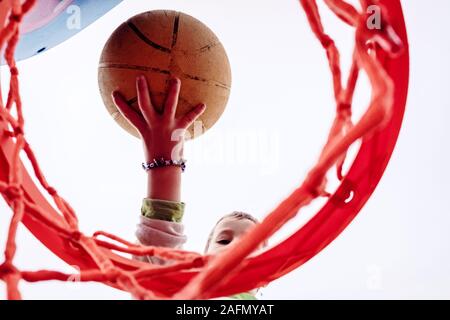 Junge schlägt ein Basketball, von unten gesehen. Stockfoto