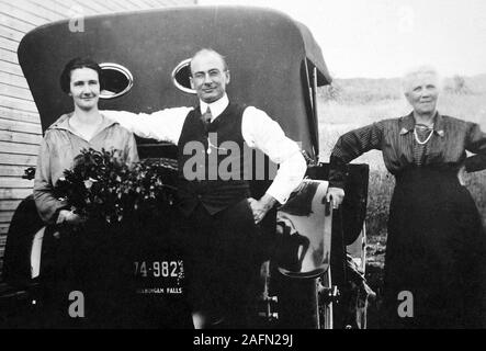 Die Schwiegermutter stellt auf der einen Seite mit Tochter und Schwiegersohn neben dem neuen Auto in Wisconsin, Ca. 1925. Stockfoto