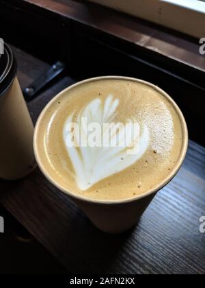 Tasse frischen Latte trinken mit herzförmigen Schaum Silhouette auf dunklen Holztisch in Coffe eingerichtete Stelle zu gehen Stockfoto