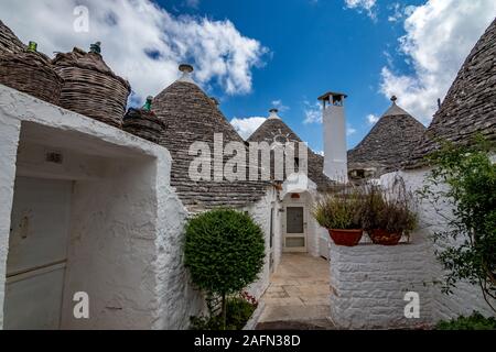 Dächer und Tore von truli, typisch weiß getünchten zylindrische Häuser in Alberobello, Apulien, Italien mit tollen blauen Himmel mit Wolken, Street View Stockfoto