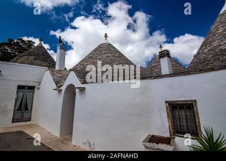 Dächer und Tore von truli, typisch weiß getünchten zylindrische Häuser in Alberobello, Apulien, Italien mit tollen blauen Himmel mit Wolken, Street View Stockfoto