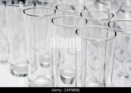 Reihen von leeren Gläser hautnah. Glas Becher am weißen Tisch. Restaurant Bar Konzept. Stockfoto