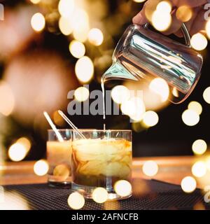 Vorbereitung von White Russian Cocktails auf der Theke auf Gummimatte. Flache DOF und Marsala tonned mit festlichen Bokeh leuchtet Stockfoto