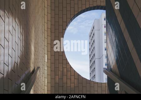 Weißes Gebäude sichtbar aus dem runden Fenster in einem gefliesten Gebäude Stockfoto