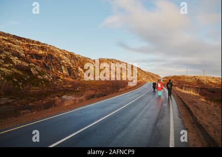 Nördliche Landstraße zwischen Hügeln mit bunten Herbst tundra Bäume und Büsche an einem bewölkten Tag. Reisen nach teriberka. Halbinsel Kola, Region Murmansk, Stockfoto