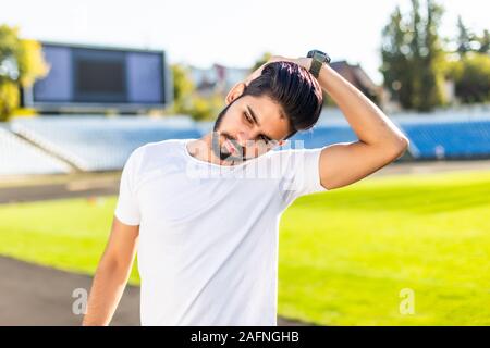 Junge Inder stretching Arme auf Laufband von Stadion Stockfoto